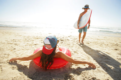woman wearing a red white and blue hat in a floatie on beach